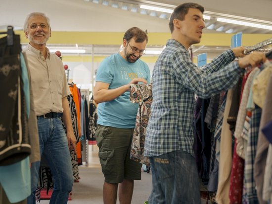 drei Maenner such in einem Klamottenladen sachen die Ihnen gefallen